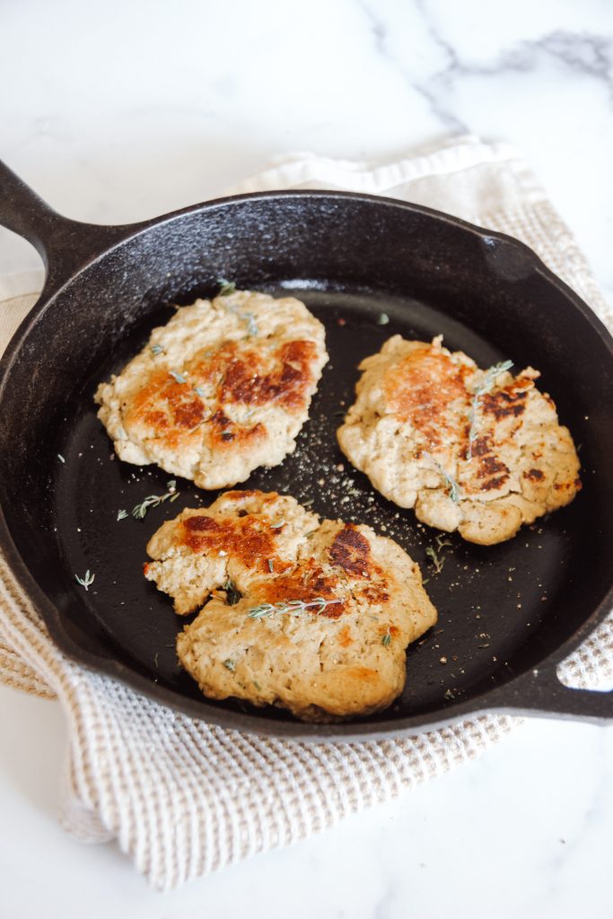 cast iron skillet with three seared vegan chicken breasts